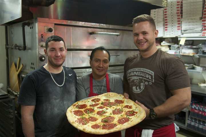 The staff at Napoli&#x27;s Pizza shows off a Margherita pie.