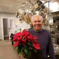 <p>Bob Mitchell gets poinsettias in place as the final touch for the church&#x27;s Christmas day community luncheon.</p>