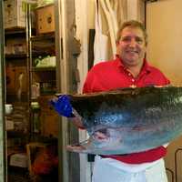 <p>Manager Scott Bennett holds up a fresh tuna.</p>