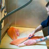 <p>Assistant Manager Zachary Redin cuts up a salmon.</p>