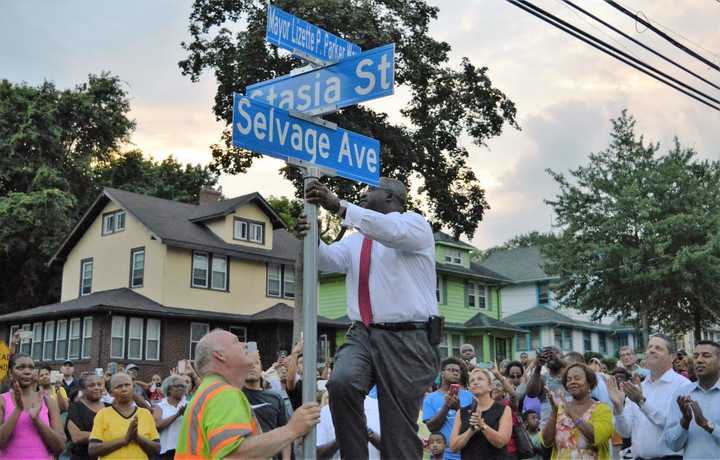 Crowd cheering after Teaneck Township Manager William Broughton unveils the new street sign at the corner of Selvage Avenue and Stasia Street.