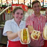 <p>Red Rooster employees show off a few of their popular hot dogs.</p>