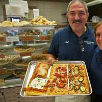 <p>Cacciatori Pizza owner Sal Triarsi and Jennie Pagliuca show off some of their popular pizzas.</p>