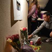 <p>Chris Vidal, 18, places a bouquet of roses under a memorial for Brooke Costanzo at a vigil at Saddle Brook High School Tuesday evening.</p>