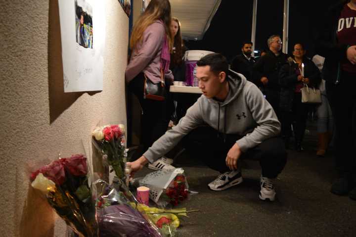 Chris Vidal, 18, places a bouquet of roses under a memorial for Brooke Costanzo at a vigil at Saddle Brook High School Tuesday evening.