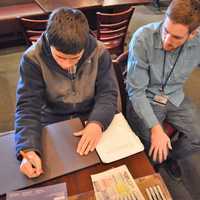 <p>Teacher Assistant Tim Smith of Dumont helps Jonathan Yammerino make a sign.</p>