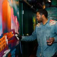 <p>Artists for Humanity Co-Founder Jordan Talbot works on his spray paint installation of the Boston Skyline at SPIN Boston</p>