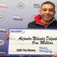 <p>Alejandro Melendez Delgado of Marshfield holds his check for a $1 million prize from the Massachusetts State Lottery</p>