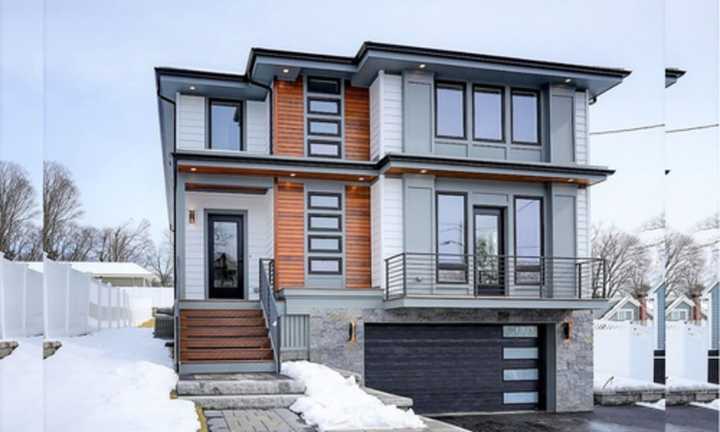 The contemporary-style colonial home features natural wood detailing on the front of the house for a modern finish.