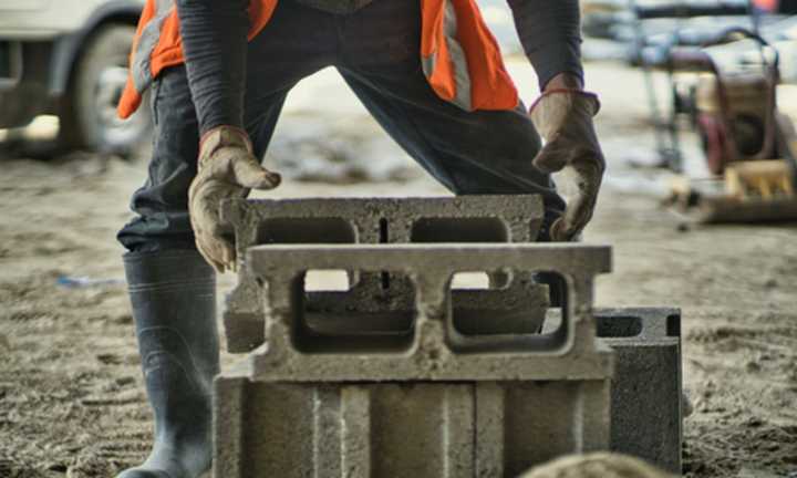 A worker lifting a cement brick.