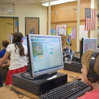 <p>Jessie Yu helps a third-grader at the Dows Lane Elementary School in Irvington during the district's recent "Hour of Code" event.</p>