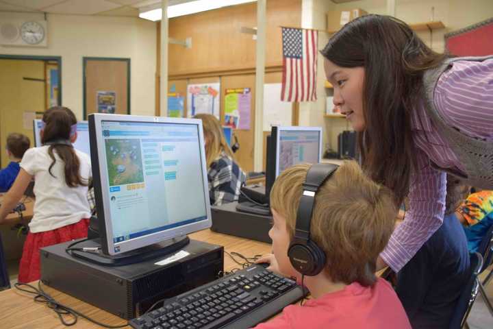 Jessie Yu helps a third-grader at the Dows Lane Elementary School in Irvington during the district&#x27;s recent &quot;Hour of Code&quot; event.