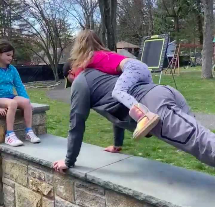 Fox Lane High School Director of Health, PE &amp; Athletics Adam Lodewick does pushups with his daughter on his back for the #FoxesUp4Hero challenge to raise funds for Northern Westchester Hospital.