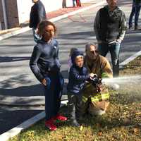 <p>Golden's Bridge Fire Department Deputy Chief Raymond Baker helps a child use a water hose at Increase Miller Elementary School.&nbsp;</p>