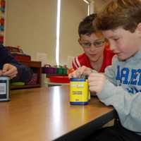 <p>Holmes School fourth graders Ronan Mirsky and Rex Kelley test batteries for electrical energy by touching metal clips to their battery ports to produce a buzzing sound.</p>