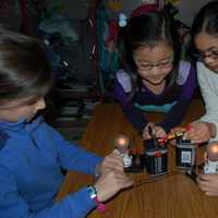 <p>Holmes School fourth graders Maggie Curran, June Qin, Apara Chandavarkar and Chloe Leimgruber discover a series circuit, a type of circuit with one path for the electrical current to flow, by combing two batteries and two lightbulbs.</p>