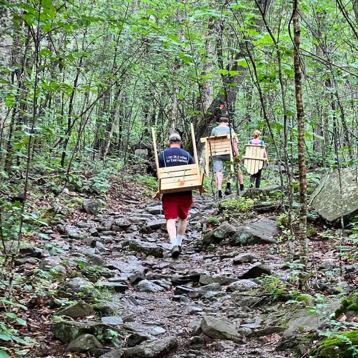 The hikers carry the chairs up the mountain.