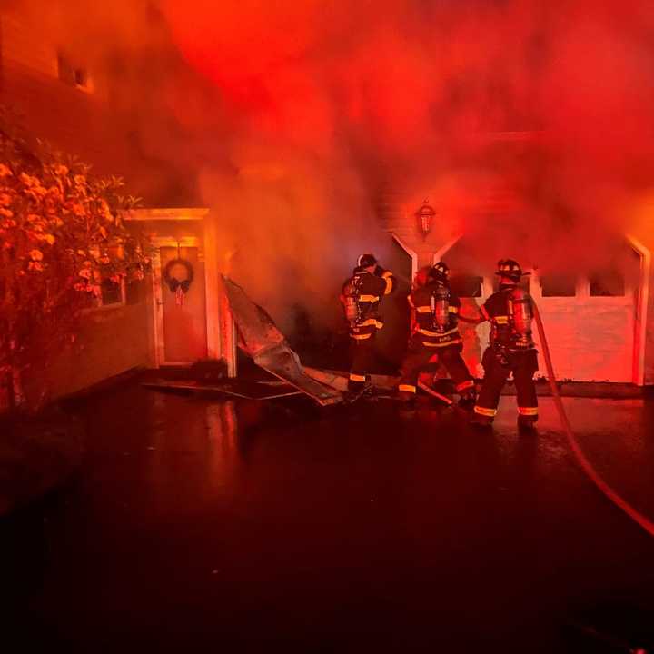 Norwalk firefighters working to keep a garage fire from spreading to the home.