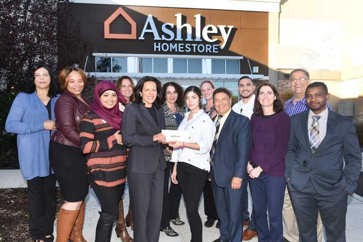 The employees of Ashley Furniture present a check to Sandy Carapezza, director of development at The Valley Hospital Foundation.