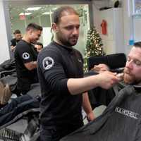 <p>Evan Vidal, owner of the Shave Bar in Hillsdale, shaves an officer.</p>