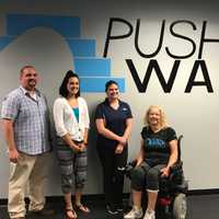 <p>Push to Walk staff Executive Director David Font, Operations Director Stephanie Lajampose, and Program Director Tiffany Warren stand with client Lois Hamilton.</p>