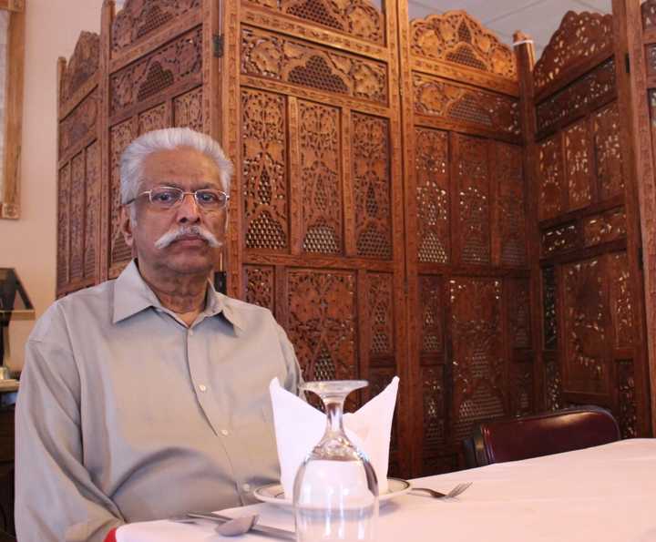 John George, owner of Priya Indian Cuisine, sits at a table inside his restaurant in Suffern.