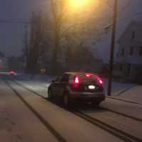 <p>Cars head out at about dawn on Thursday on snow-covered roads in Danbury. A couple of inches of snow are already on the ground.</p>