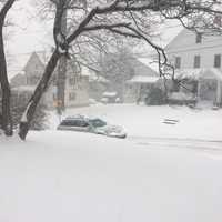 <p>A heavy blanket of snow already covers Danbury at 8 a.m. Thursday as a car heads up a residential street.</p>