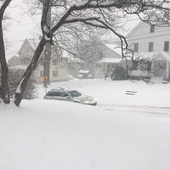 A heavy blanket of snow already covers Danbury at 8 a.m. Thursday as a car heads up a residential street.