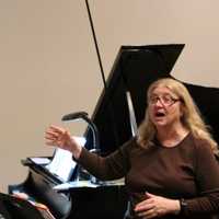 <p>Christine Tenore accompanies Cantiamo Choir on piano as Marlane Tubridy conducts during a rehearsal for an upcoming concert.</p>