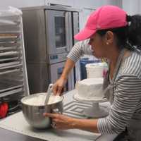 <p>Regina Heredia works on a red velvet cake she will slice up for sale. Cindy Capitani</p>