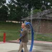 <p>Danbury Mayor Mark Boughton dodges the drops at the new spray park at Kenosia Park.</p>