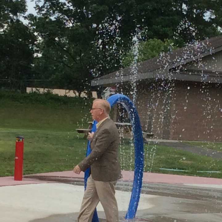 Danbury Mayor Mark Boughton dodges the drops at the new spray park at Kenosia Park.