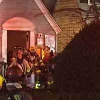 <p>Some flames are visible as Stamford firefighters work the front entrance of a home at 26 Underhill St. late Wednesday afternoon.</p>