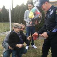 <p>Grandfather David Samiel Sr. and Father Barry Samiel help David Samiel II exchange thank you cards with Garfield Police Officer Francisco Sanchez.</p>