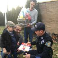 <p>Grandfather David Samiel Sr. and Father Barry Samiel help David Samiel II exchange thank you cards with Garfield Police Officer Francisco Sanchez.</p>