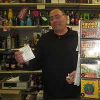 <p>Lewis Stern holds up a Powerball ticket at Yorktown Wine and Liquors.</p>