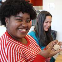 <p>A smiling woman holding an uncooked dumpling.</p>