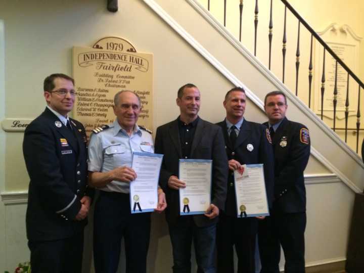 Evan Tilley, second from left, Sam Mouziyk, center, and Firefighter Jerry McGuire, second from right, pose with their proclamations.