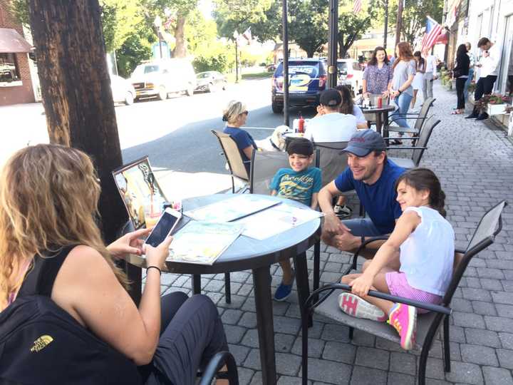 Kristin Dubois takes a photo of her kids, 8-year-old Christian and 7-year-old Ava, as they pose with U.S. Sen. Chris Murphy at Jacqueline&#x27;s in downtown Bethel on Thursday morning.