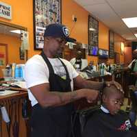 <p>Owner Harvey Robertson puts the finishing touches on a free haircut for 8-year-old Kiieer at North East Barbershop in Bridgeport.</p>