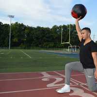 <p>Fitness trainer Kevin Saenz holds a medicine ball above his head as he performs walking lunges down the Hackensack High School track.</p>