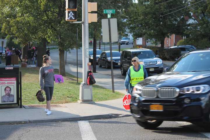 A student and crossing guard stand near the busy intersection of South Front Street and East Clinton Avenue in Bergenfield, not far from the high school and railroad tracks. 