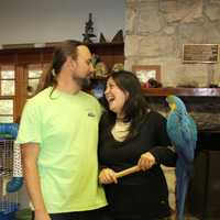 <p>Marc and Kimberly Gussen stand in the nature center building in Closter with their macaw, Monty. </p>