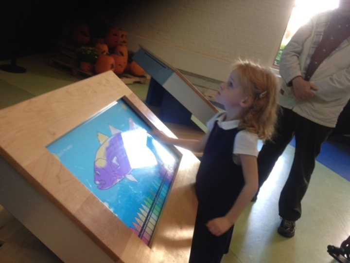 Maeve Nelson, 4, of Norwalk, colors in a fish under the watchful eye of her grandparents, Dan and Sheila Kuhn of Danbury, at the interactive board at Norwalk&#x27;s Maritime Aquarium.