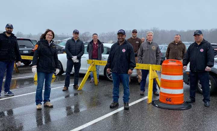 A group of local law enforcement and government leaders deliver food and goodies to workers at a COVID-19 testing site.