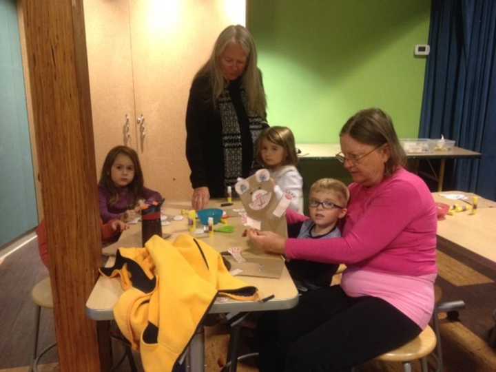 William Salvatore, 3, of Fairfield, and his grandmother, Ellen Nelly, inspect the paper bag puppet he created at Stepping Stones&#x27;s Jumpstart Read for the Record program in Norwalk as other participants finish up their crafts.