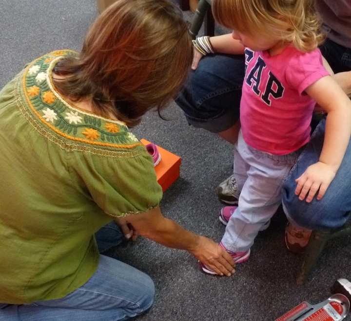 Luann Rush of PedAgree Shoes checking the fit on 2-year-old Avery&#x27;s new pink sneakers. 