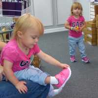 <p>Emilia, 2, double checks the fit of her new sneakers, while her twin sister, Avery, takes her sneakers for a test drive. </p>