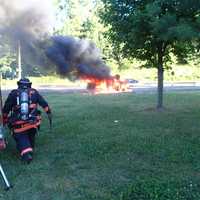 <p>The Westport Fire Department approaches a car fully engulfed in flames on Saturday evening on the Merritt Parkway.</p>